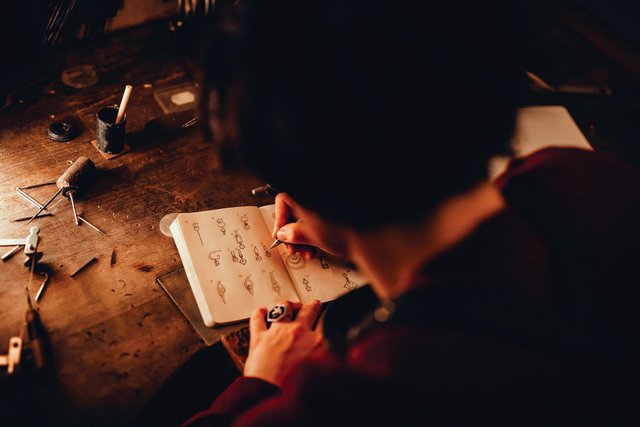 Morgane Meylan, bijoutière, dessine l'esquisse d'un bijoux sur un cahier dans son atelier de Lausanne.