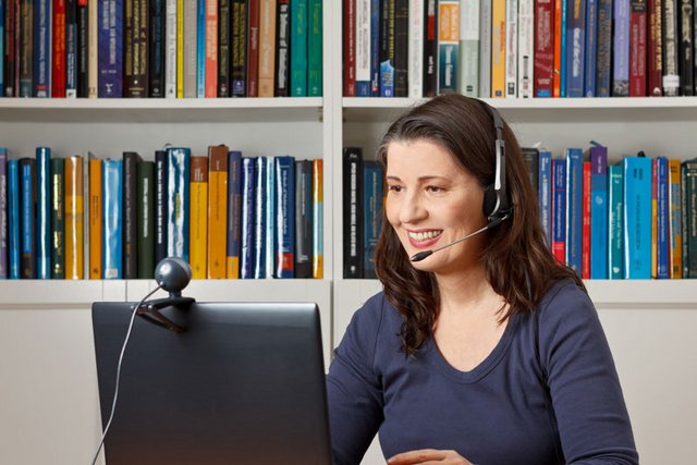 une femme en visioconférence, chez elle, avec son ordinateur