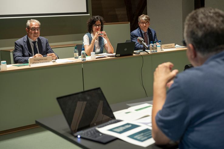 Les trois personnes assises à une table durant la conférence de presse.