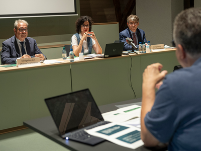 Les trois personnes assises à une table durant la conférence de presse.